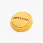 A round yellow plush toy with the word "Squeakie Pattiez - Zippy Coin" embroidered on it.