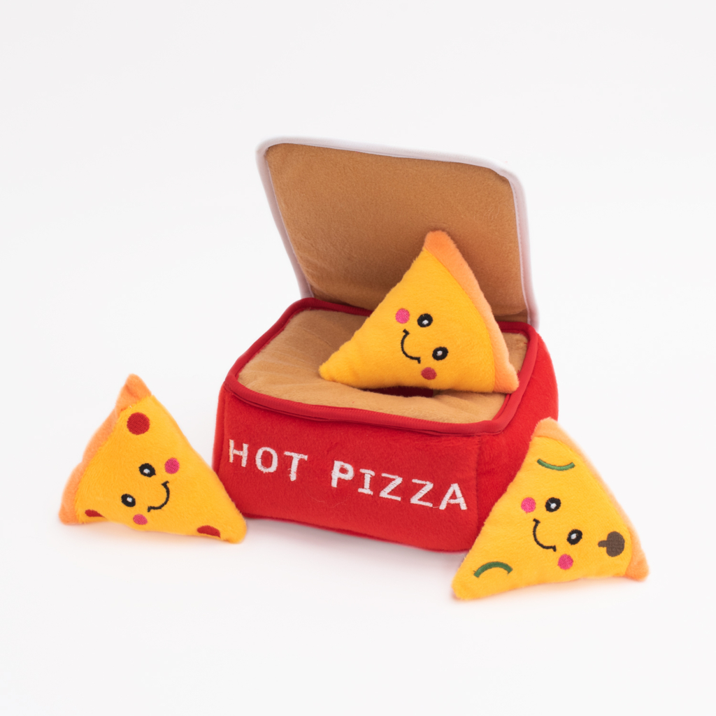 Three plush toy pizza slices with smiling faces are placed near and inside a red and beige fabric pizza box that reads 