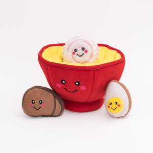 Zippy Burrow® - Ramen Bowl in the shape of a red bowl with a smiling face, containing additional small plush food items including a smiling egg and a brown plush with a face.