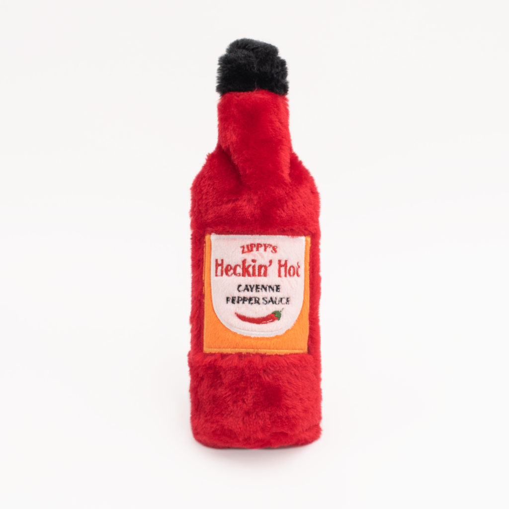 A plush toy shaped like a red hot sauce bottle with the label 