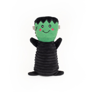 A Halloween Colossal Buddie - Witch designed to look like a friendly green monster with a stitched smile, rosy cheeks, black zigzag hair, and a black textured body. The toy has outstretched arms and stands upright.