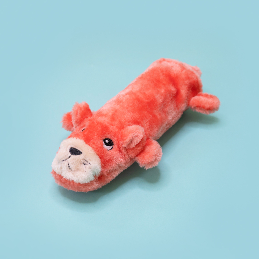 A plush toy shaped like an orange animal, possibly a dog or bear, lies on a light blue background.

Bottle Crusherz - Otter lies on a light blue background.