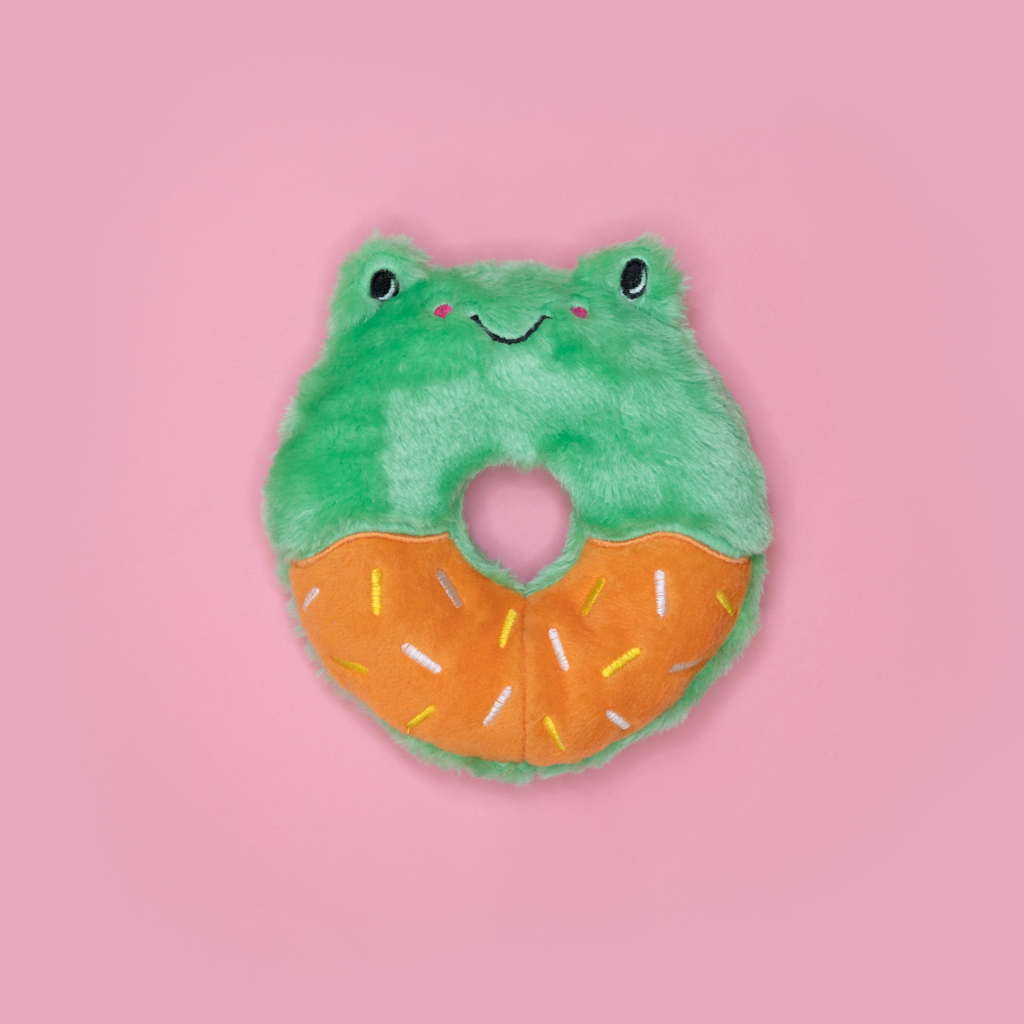 A Donutz Buddies - Frog shaped like a donut with green fur resembling a frog's face on top and an orange bottom with colorful sprinkles, set against a pink background.