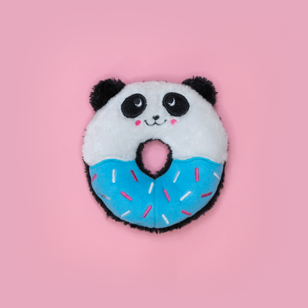 A Donutz Buddies - Panda with panda face details and a blue bottom half decorated with pink and white sprinkles, set against a pink background.
