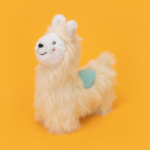 A Wooliez - Larry the Llama with cream-colored fur and a blue saddle is set against a solid orange background.