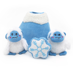Two Holiday Burrow® - Yeti Mountain toys with smiling faces, a plush snowflake, and a soft blue mountain with a white, fluffy top.
