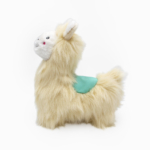 Plush llama toy with beige fur and a green saddle, standing and facing left on a white background.