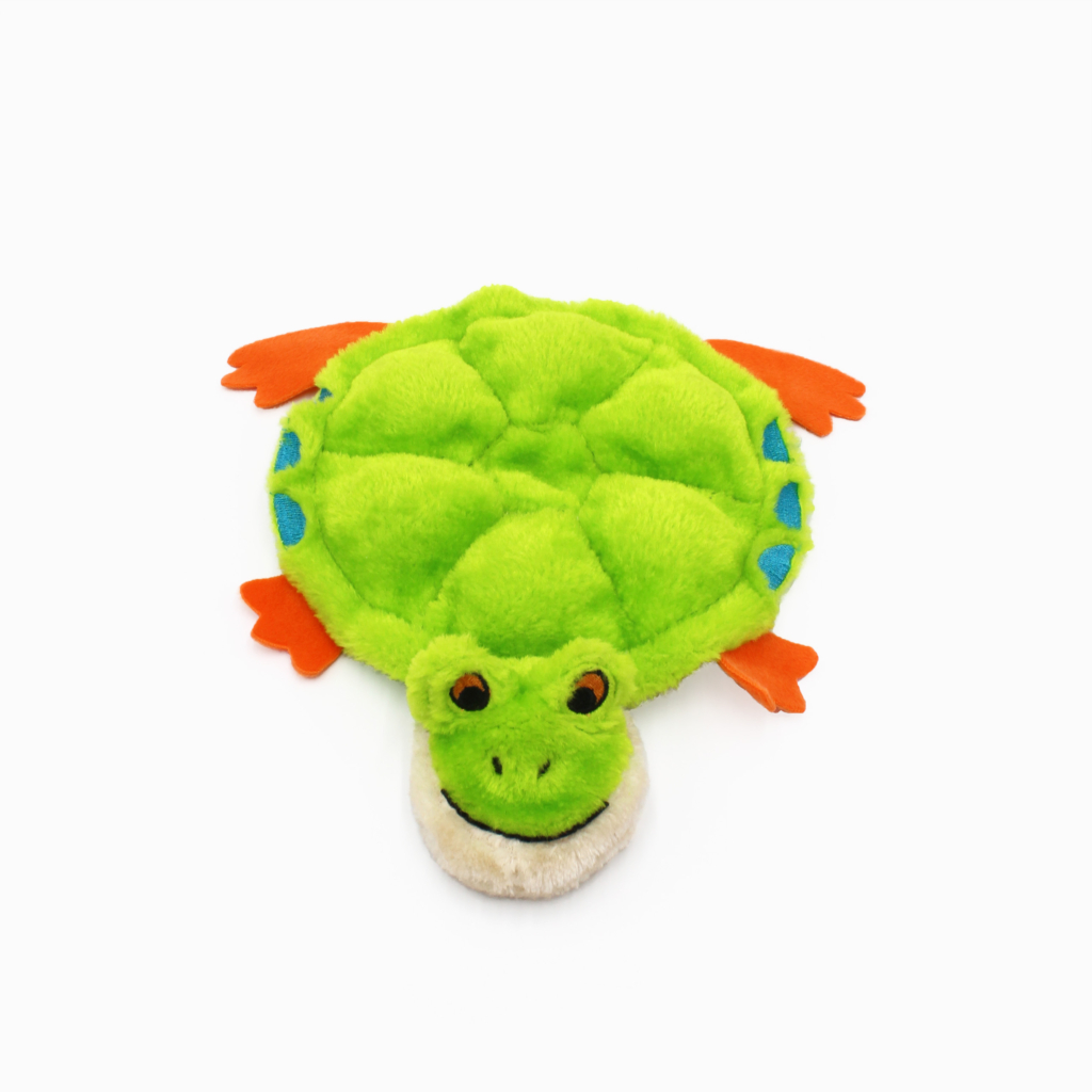 A green plush turtle toy with orange flippers and blue spots on its shell, lying on a plain white background.