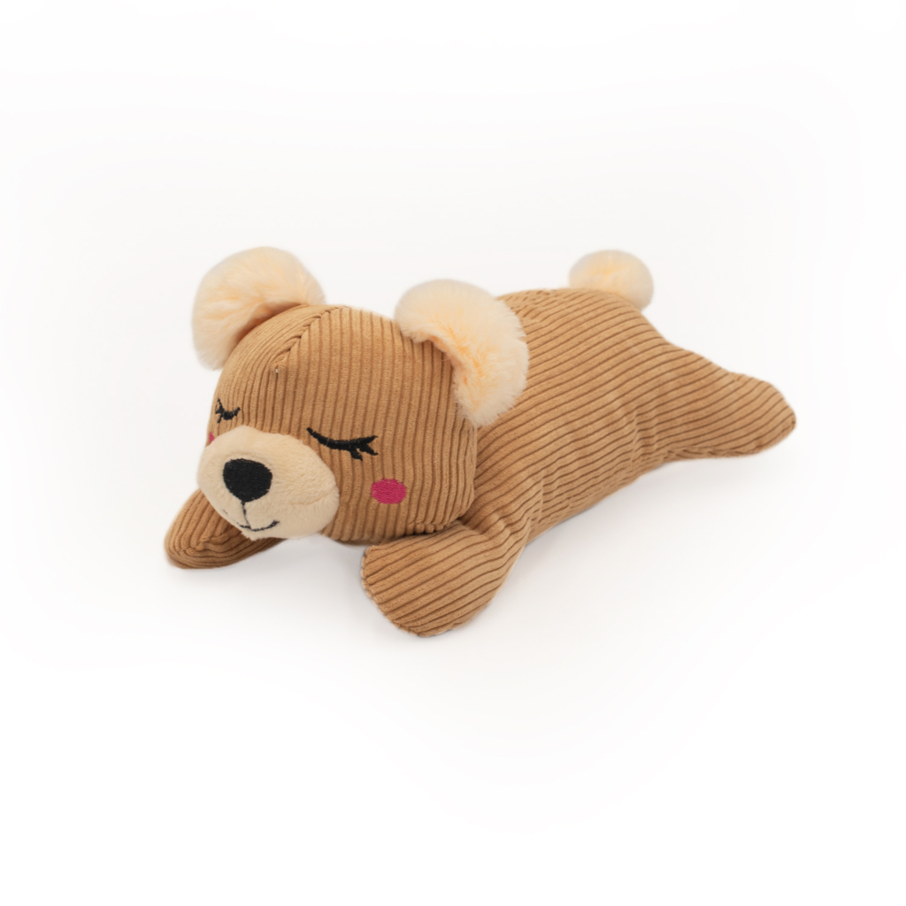 A Snooziez with Shhhqueaker - Bear lying on its stomach with closed eyes, pink cheeks, and beige ears.