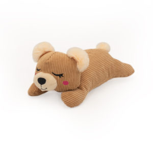 A Snooziez with Shhhqueaker - Bear lying on its stomach with closed eyes, pink cheeks, and beige ears.