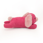 A pink Snooziez with Shhhqueaker - Bunny resembling a lying down dog with floppy ears and a small tail on a white background.