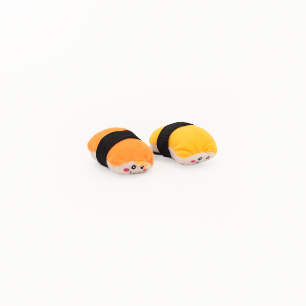 Two ZippyClaws® NomNomz® - Sushi with faces, featuring orange and yellow toppings, wrapped in black bands, on a white background.