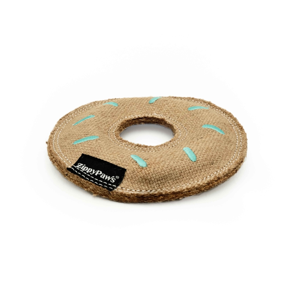 A round dog toy made of brown burlap material, resembling a donut with a hole in the center and blue stitching on top. A small black tag reads “ecoZippy Jute Donutz.”