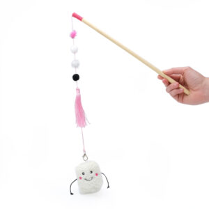 A hand holds a ZippyClaws® ZippyStick - Marshmallow with a pink tip, featuring hanging pom-poms, a pink tassel, and a plush white smiling figure with pink cheeks and black arms.
