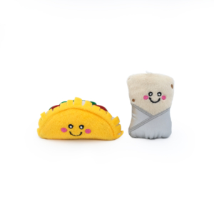 Two ZippyClaws® NomNomz® - Taco and Burrito plush toys with smiling faces: one is a yellow taco with toppings, and the other is a grayish burrito wrapped in a tortilla. Both are on a plain white background.