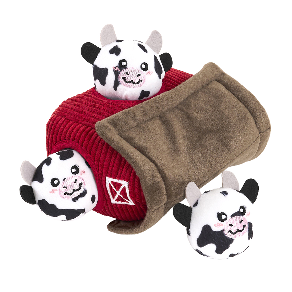 Three plush cows and a red and brown plush barn from the Zippy Burrow® - Zippy Meal set are shown. The barn has an opening, with the cows partially inside and outside of it.