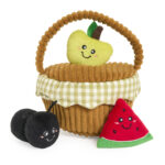 A Zippy Burrow® - Zippy Meal plush basket with a handle holds a smiling plush apple, while smiling plush cherries and watermelon sit in front.