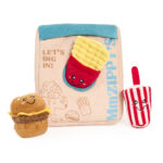 Plush toys shaped like a hamburger, fries, and a popsicle with smiling faces, arranged in front of the Zippy Burrow® - Zippy Meal soft bag featuring the phrases “MhZIPPY’s” and “LET’S DIG IN!”.